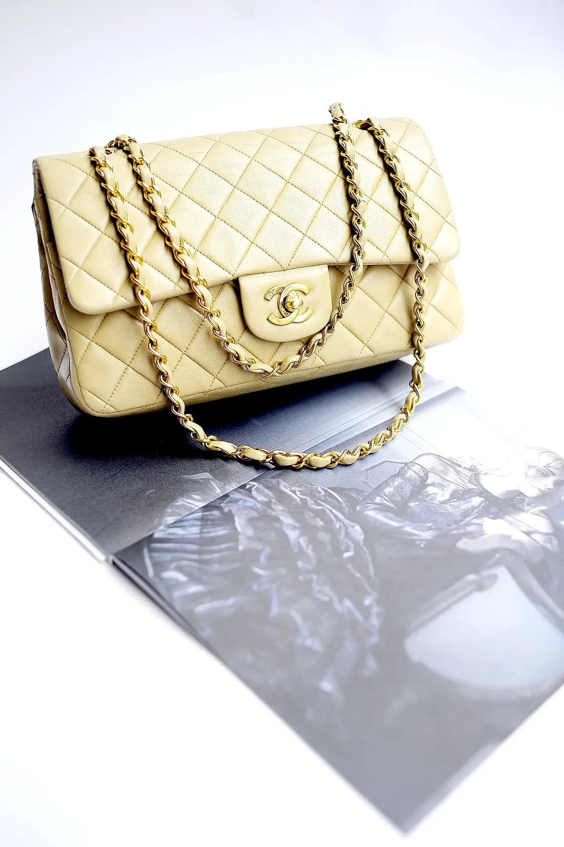 A beige quilted lambskin Chanel flap bag with a gold chain strap