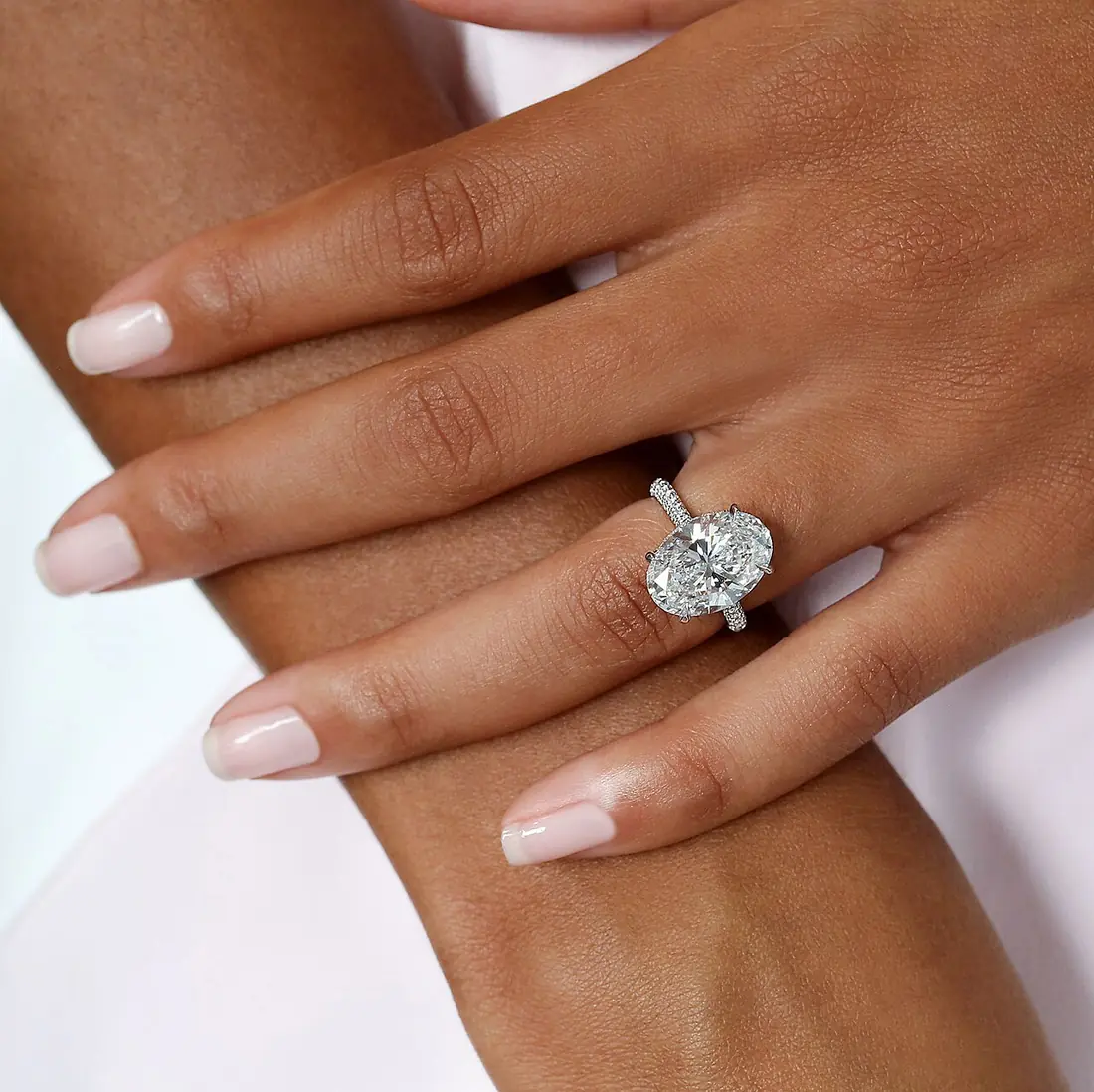 An oval diamond in a prong solitaire setting on a pavé-set white gold band