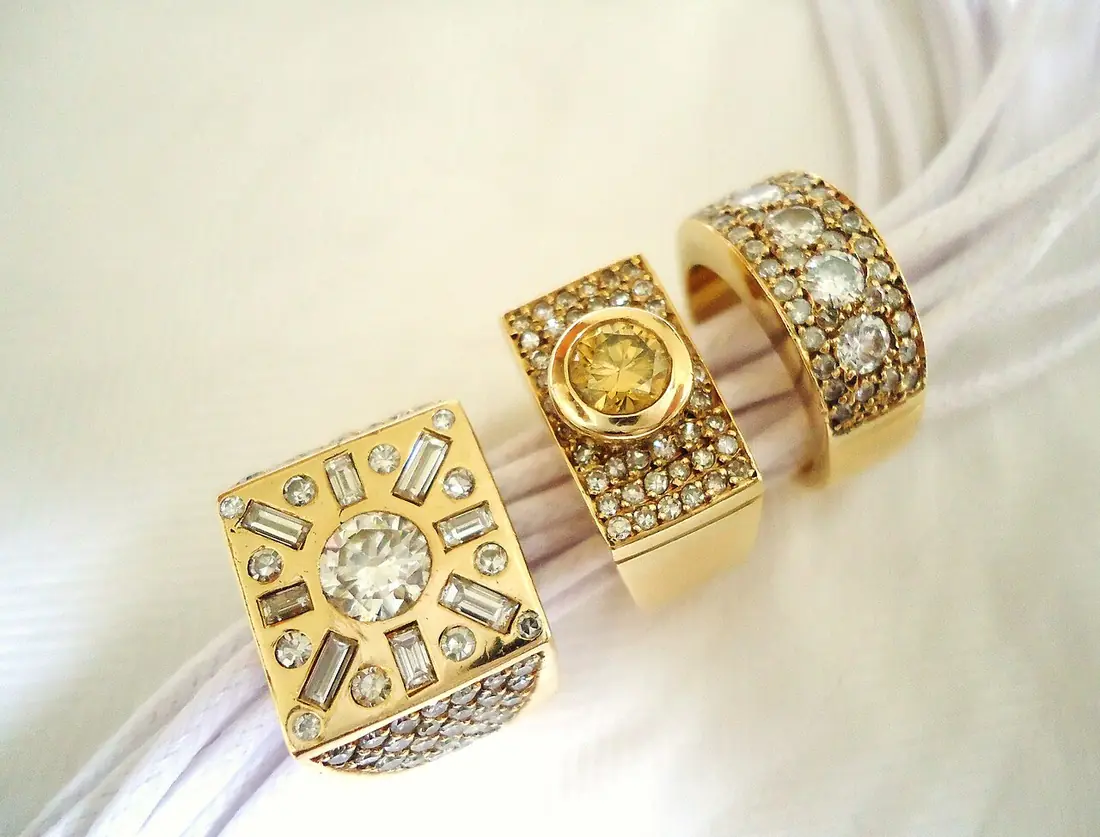 Three gold rings set with diamonds resting on white fabric