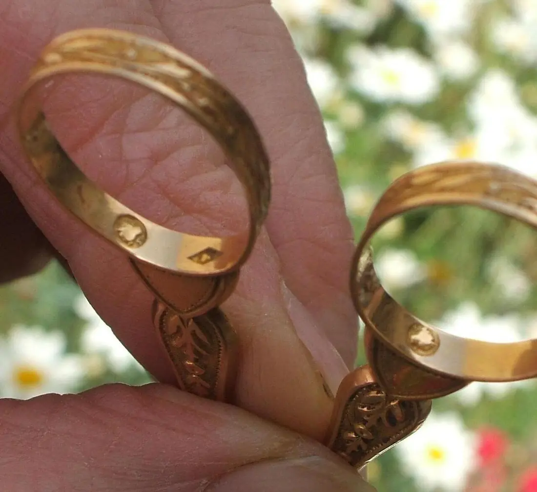 Close-up of hallmark punches stamped inside two gold wedding bands
