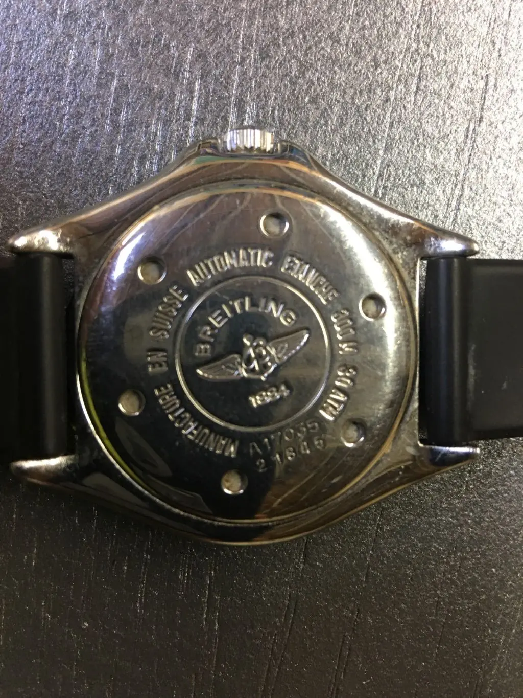 A steel watch caseback engraved with its water resistance rating in metres and feet plus reference and serial numbers
